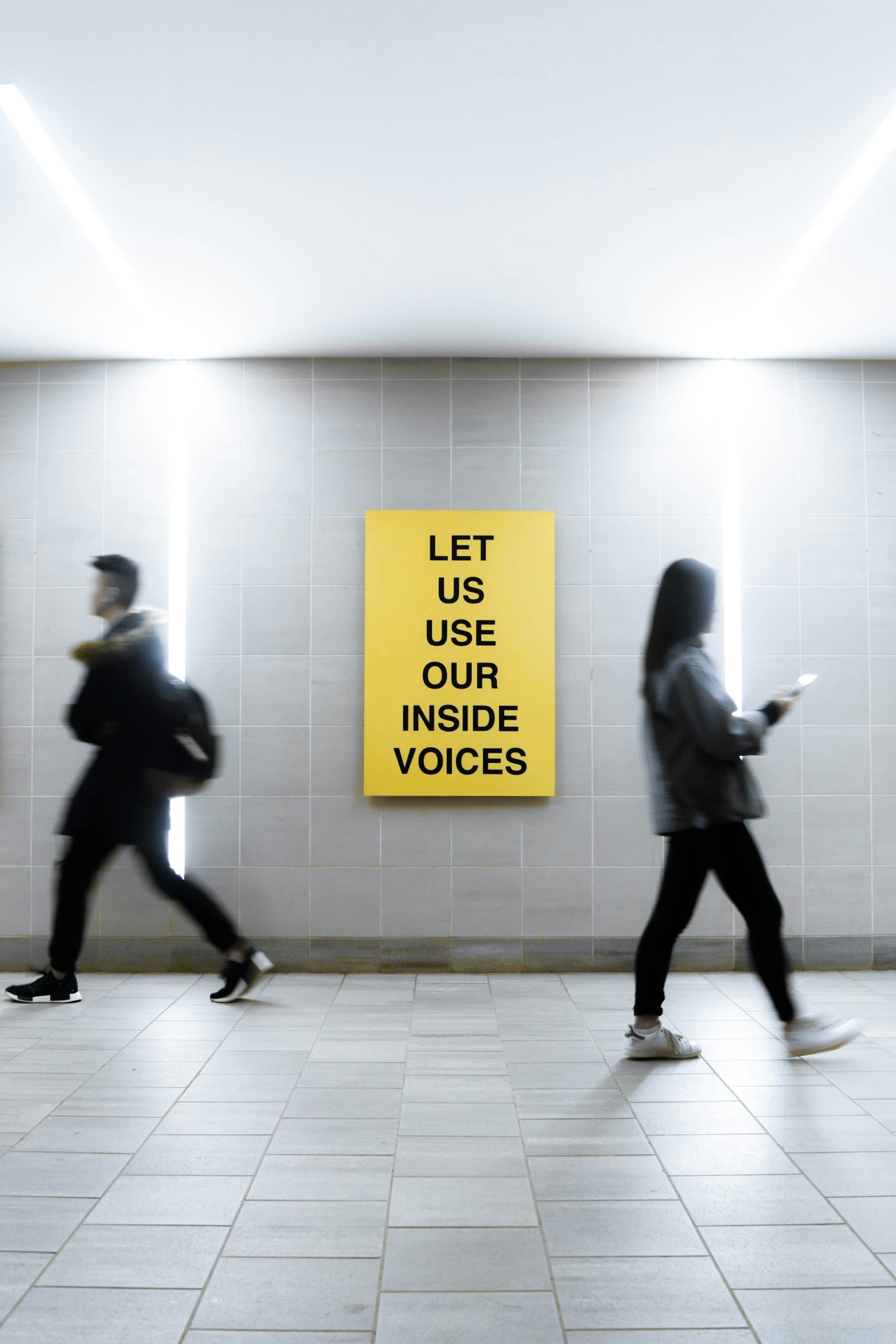 Gelbes Plakat in einem Gang: Let us use our inside voices